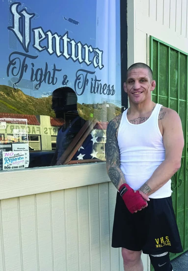 Bobby Taylor in hand wraps outside Ventura Fight & Fitness, in front of the painted storefront window